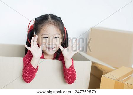 Asian Girl Playing In The Box At Home. Kid Sitting Inside Box With Attractive Smiling.