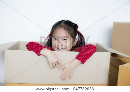 Asian Girl Playing In The Box At Home. Kid Sitting Inside Box With Attractive Smiling.