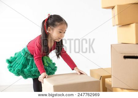 Attractive Asian Girl Try To Move A Box At Home. Kid Holding Box With Attractive Smiling. Kid With H