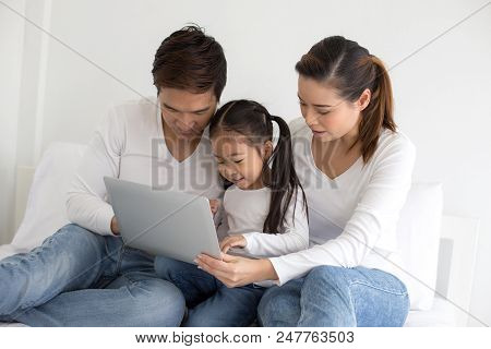 Attractive Little Girl Using Laptop With Mom And Dad Together. Girl Learning To Use Laptop. Happy Fa