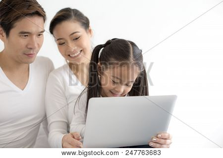 Attractive Little Girl Using Laptop With Mom And Dad Together. Girl Learning To Use Laptop. Happy Fa