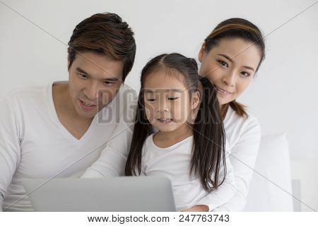 Attractive Little Girl Using Laptop With Mom And Dad Together. Girl Learning To Use Laptop. Happy Fa