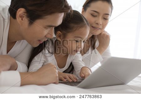 Attractive Little Girl Using Laptop With Mom And Dad Together. Girl Learning To Use Laptop. Happy Fa