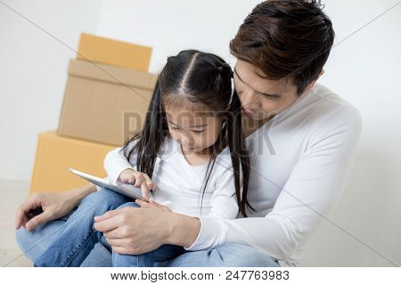 Little Girl Using Tablet With Dad And Mon Together At Home. People With Technology Concept.