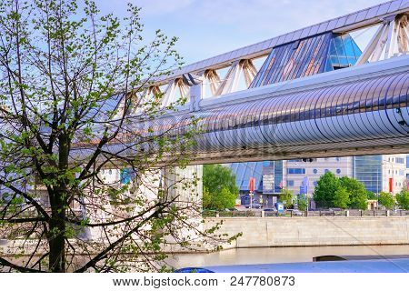 Cityscape - View Of The Embankment And Futuristic Glass Bridge Over The River In The Spring Sunny Da