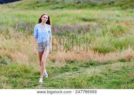 Happy Smiling Young Girl Wearing Blue Jeans Jacket And Shorts Is Standing In The Field