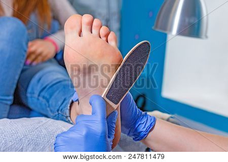 Master During A Pedicure. The Process Of Professional Pedicures. The Wizard In The Mask Causes The G