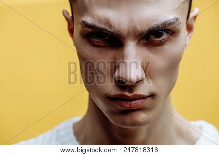 Close Up Portrait Of Angry Or Agressive Young Man Posing Against Yellow Background With Fround Brows