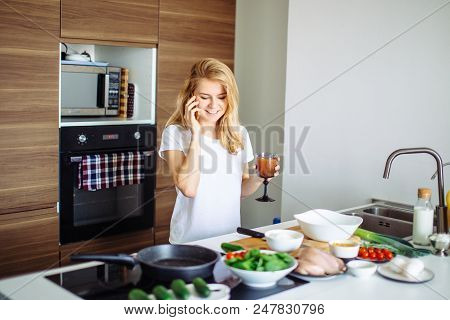 Blonde Student Girl Standing At The Table With Food Ingredients Placed In Line, Going To Make Dinner