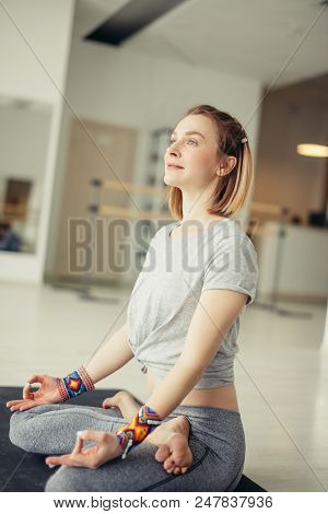Sporty Woman Practicing Yoga Sitting In Padmasana. Young Woman In Lotus Pose Doing Breathing Exercis