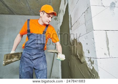 Plasterer applying plaster on block wall. Rennovation