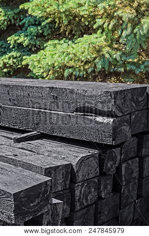 Set Of New Creosote Impregnated Wooden Sleepers Are Stacked On Each Other Against The Background Of 