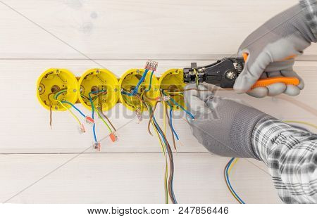 Hands Of Electrician Installing Electrical Socket With Screwdriver In The Wall In New Wooden House