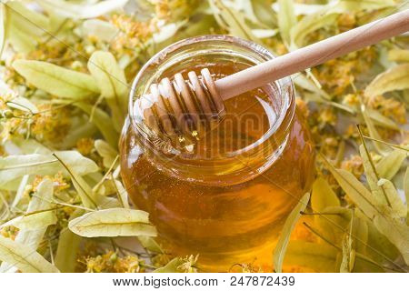 Glass Jar Of Honey On The Background Of Linden Blossoms