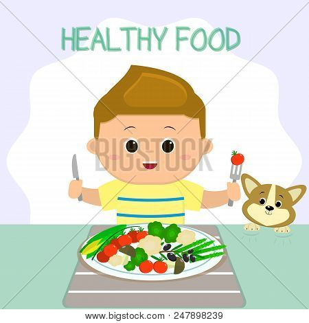 A Boy In A T-shirt Is Sitting At A Table, A Plate Of Vegetables. The Puppy Looks Like Shit. Healthy 