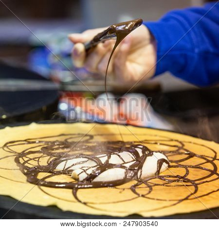 Street vendor prepares traditional chocolate and banana crepes at a street market in Berlin. 