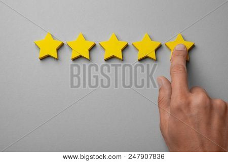 Five Golden Yellow Stars Out Of Five. Man Points Finger At The Star, Puts Rating, Recalls