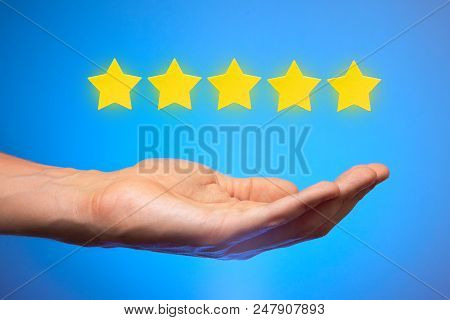 Five Golden Yellow Stars Out Of Five. Man Holds Star On The Palm Of His Hand, Puts Rating, Reviews. 