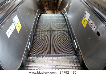 empty electric escalator with warning signs how to use sticked on the side, stair entrance moving down to subway train station, selective focus
