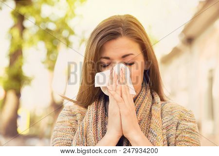 Woman With Allergy Symptoms Blowing Nose Outdoors