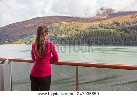 Woman tourist on scenic Alaska cruise in Glacier bay sailing in inside passage. USA vacation travel. Tourist watching autumn foliage passing by, nature outdoors.