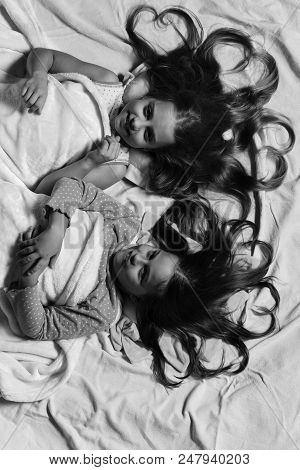 Girls Lie On Pink Bed Sheets Background. Schoolgirls In Pink Pajamas Wallow On Colorful Pillows, Top