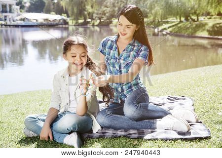 Mom Is Sitting Behind Her Daughter And Braiding Heer Hair. She Is Taking One Elastic From Child. Gir