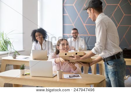 Male Deliveryman Giving Pizza Cardboard Box To Smiling Female Employee Ordering Takeout Food For Lun