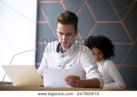 Concentrated Male Employee Reading Document, Preparing Company Report Al Laptop In Coworking Space, 