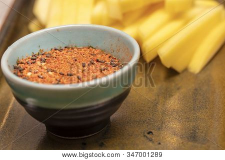 Small Bowl Of Seasonings Used To Make Sushi And Julienne Cut Mango On A Ceramic Plate