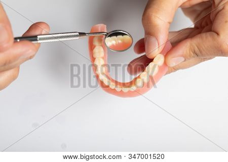 Denture prosthesis in doctor orthodentist dentist hand, checking with mirror