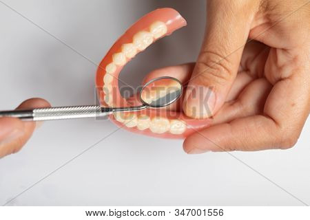 Denture prosthesis in doctor orthodentist dentist hand, checking with mirror