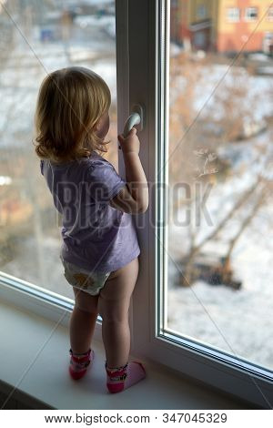 A Little Girl Standing In Front Of A Window