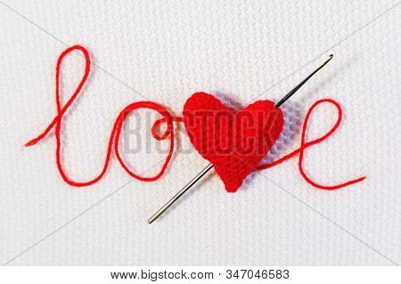 Valentines Day, Wedding Backdrop. Crochet Hook Pierced Red Knitted Volume Heart Like An Arrow In Wor