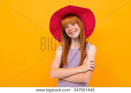Young Girl In Purpe T-shirt With Red Hair And Pink Hat Smiles And Hopes For Something Isolated On Ye