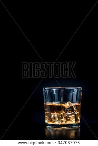 Whisky, Whiskey, Bourbon Or Cognac With Ice Cudes On Black Stone Table