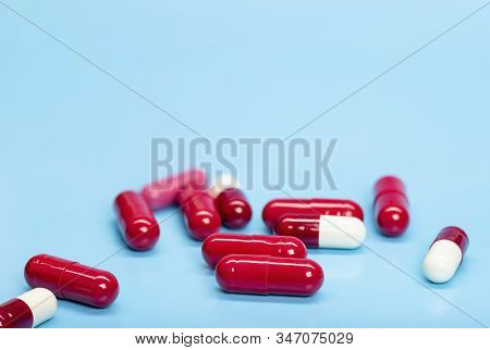 Red-white Antibiotic Capsules On A Blue Background