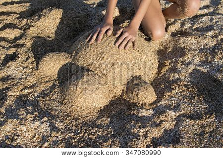 Sand Turtle Sculpture Top View. Girl Sculpts From River Sand A Turtle On The Beach.