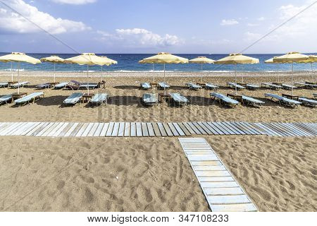 Empty Sunbeds And Umbrella On Afandou Beach Near Faliraki (rhodes, Greece)
