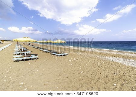 Empty Sunbeds And Umbrella On Afandou Beach Near Faliraki (rhodes, Greece)