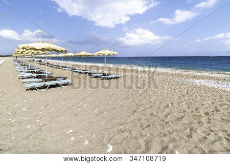 Empty Sunbeds And Umbrella On Afandou Beach Near Faliraki (rhodes, Greece)