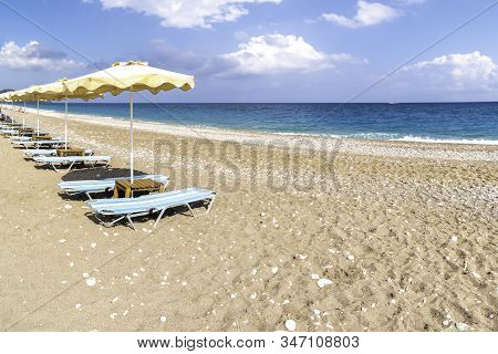 Empty Sunbeds And Umbrella On Afandou Beach Near Faliraki (rhodes, Greece)