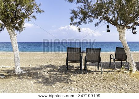 Empty Chairs Under Tree With View Of Sea On Afandou Beach Near Faliraki (rhodes, Greece)