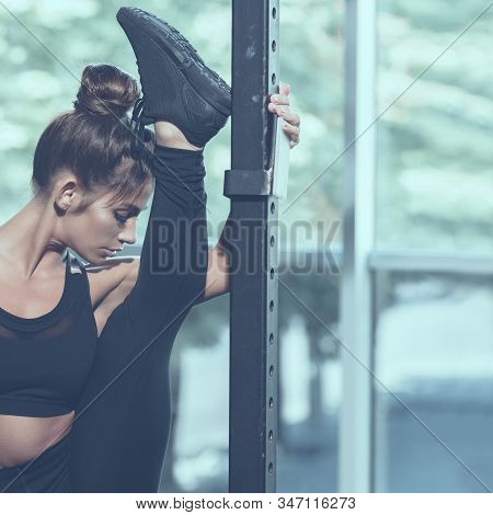 Portrait Of Young Atrractive Woman Doing Split In Gym, Image With Cold Vintage Toning