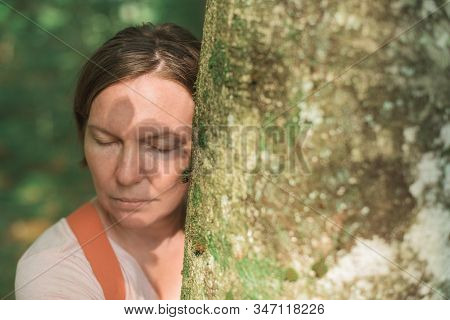 Woman Is Hugging Tree Trunk In Forest, Female Environmentalist With Her Arms Around The Tree, Select