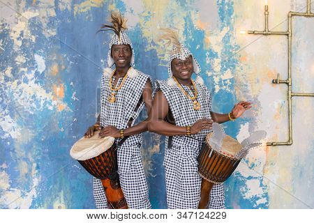 A Group Of People In Traditional African Costumes Playing Jembe Drums