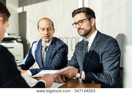 Group Of Confident Successful Business People Reviewing And Signing A Contract To Seal The Deal At B