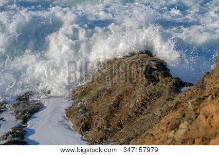 Large Ocean Waves Crash Against Coastal Stones And Rocks On A Clear Sunny Day On The European Coast.