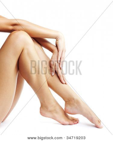 Gambe di donna isolate su sfondo bianco, bellissimi piedi femminili abbronzate e concettuale della spa mani