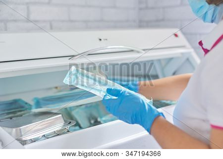 Female Nurse Doing Sterilization Of Dental Medical Instruments In Autoclave. Sterilization Departmen